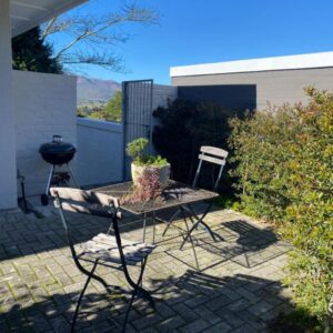 A sunny patio with a braai and bistro chairs at Kortrijk Paarl Self Catering in Paarl