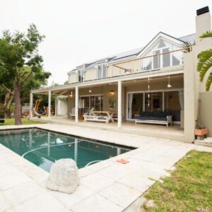 A two-storey house with a covered veranda and a swimming pool at L'Escapade in Kommetjie