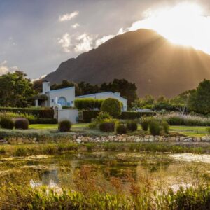 A house in front of a mountain with a pond at La Cabriere Country House in Franschhoek
