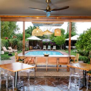 A patio with a pool and tables and chairs at La Pension Guest House in Oudtshoorn