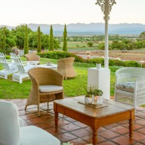 A patio with white chairs and a table with a view at La Plume Boutique Hotel & Spa in Oudtshoorn