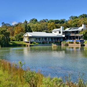 A lodge beside a lake surrounded by trees at Ladybird Boutique Hotel at Kanonkop in Stellenbosch