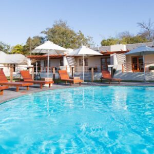 A large swimming pool with chairs and a house at Lauradale Accommodation in Stellenbosch