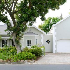 A white house with a tree and a garage at Laurel Cottage in Franschhoek