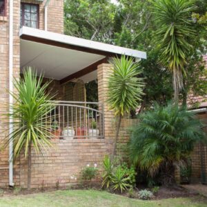 A brick house with a garage with palm trees at Lavender Lane in George
