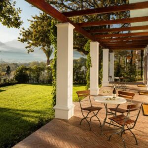 A patio with a table and chairs on a lawn at Leeu Estates in Franschhoek