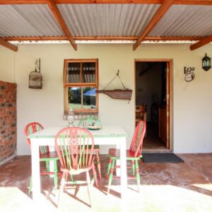 A patio with a table and chairs and a brick wall at Lentelus Guesthouse Pty Ltd in George