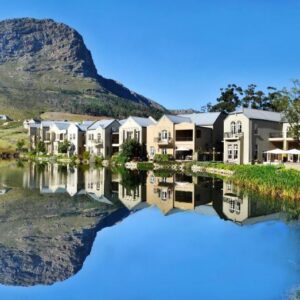 A row of houses next to a river with a mountain at L'ermitage - Franschhoek Chateau & Villas in Franschhoek