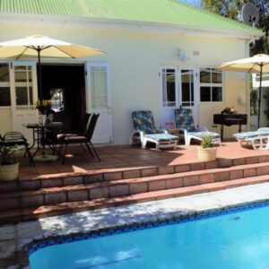 A patio with a pool and chairs and umbrellas at Mafunyani Cottage in Franschhoek