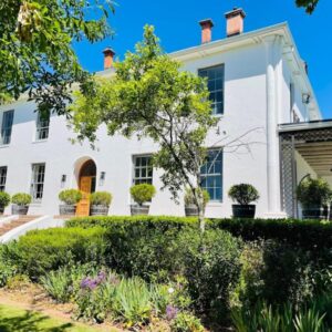 A white house with a garden in front of it at Manor House, De Zalze in Stellenbosch
