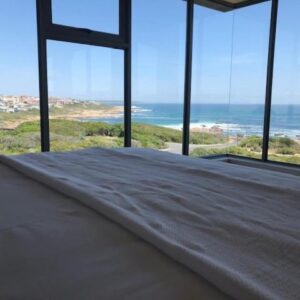 A bedroom with a bed with a view of the ocean at Marine 5 Boutique Hotel in Gansbaai