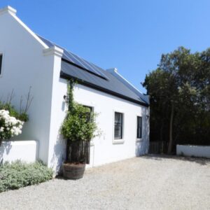 A white house with flowers on the side of it at Matjesfontein Estate Keurbooms Chalet in Plettenberg Bay
