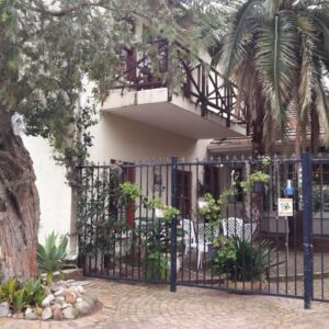 A wrought iron fence in front of a house with a tree at Mavilla Stellenbosch B&B in Stellenbosch