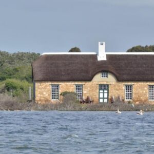 A house on the water with two ducks in front of it at Melkkamer by De Hoop Collection in De Hoop Nature Reserve