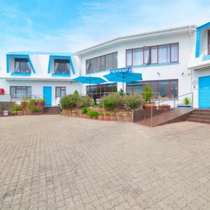 A large white building with blue doors and windows at Mermaid Guest House in Struisbaai