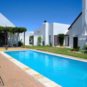A swimming pool with chairs next to a house at MM Good Times in Gansbaai
