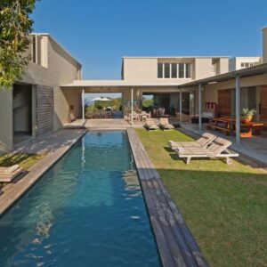 A backyard with a pool with benches and a house at Mosselberg on Grotto Beach in Hermanus