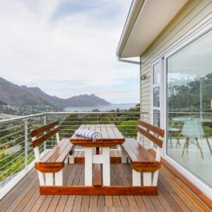 A porch with a wooden table and chairs on a balcony at Mount Bay in Hout Bay