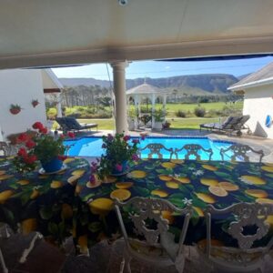 A table with a colorful table cloth with a pool at Mulligans Guest Lodge in Hermanus