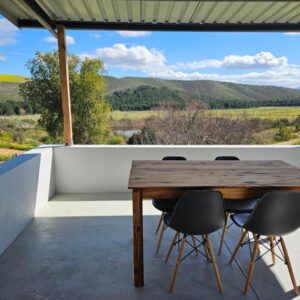 A wooden table on the balcony of a house at Nagtegaal Farm Stay in Swellendam