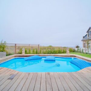 A swimming pool with a wooden deck and a house at Nature Nest Cottage in Grotto Bay