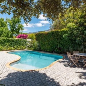 A swimming pool in a backyard with a table and chairs at Oak Manor Boutique Guest House in Cape Town