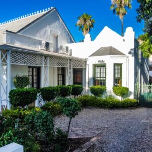 An old white house with trees and bushes at Oakdene Guest House in Oudtshoorn