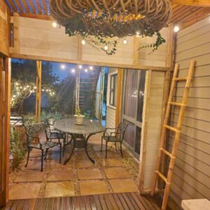 A patio with a table and chairs and a ladder at Ocean Whisper Cottage, Sunset, Sizzle and Rest in Wilderness
