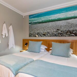A bedroom with a bed and a painting on the wall at Oceans Guest House & Luxurious Apartments in Struisbaai