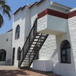 A white building with a staircase on the side of it at Oom Piet Accommodation in Gansbaai