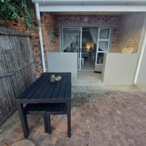 A black picnic table in front of a house at Petite Selfcatering Accommodation Struisbaai SA in Struisbaai