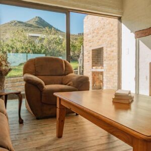 A living room with a couch and a table and a chair at Phillipskop Eco-Chalets in Stanford