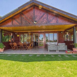 A wooden house with a patio with chairs and tables at Piesang Valley Lodge in Plettenberg Bay