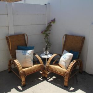 Two wicker chairs and a table on a patio at Pik & Pikkie Self catering apartments in Lambertʼs Bay