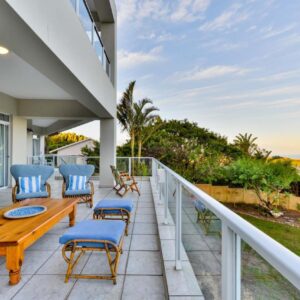 A patio with a wooden table and chairs on a balcony at Plettenberg View in Plettenberg Bay