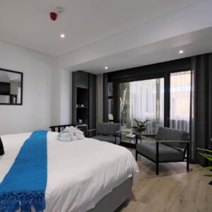 A bedroom with a white bed and a blue throw at Point B Guest House in Cape Town