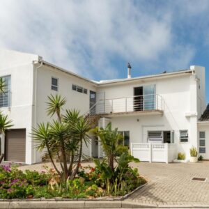 A white house with palm trees in front of it at Pro Moni's Guesthouse in Muizenberg