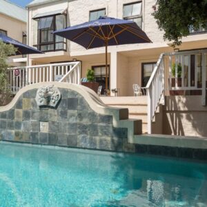 A swimming pool with a staircase and an umbrella at Protea Hotel by Marriott Dorpshuis & Spa Stellenbosch in Stellenbosch