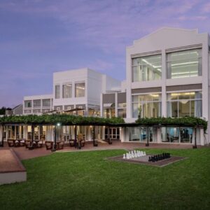 A large white building with a lawn in front of it at Protea Hotel by Marriott Stellenbosch & Conference Centre in Stellenbosch