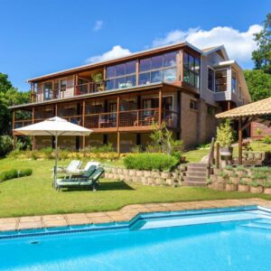 A house with a swimming pool in front of it at Pumula Lodge 4 Star Guesthouse Knysna in Knysna