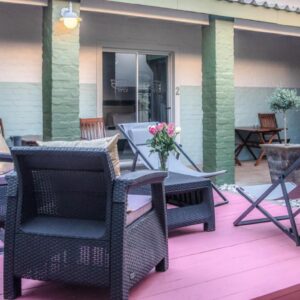A patio with wicker chairs and a table on a deck at Puza Moya Guest House in Langebaan
