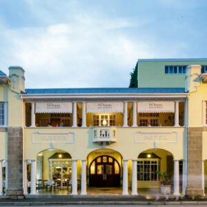 A large yellow building with arched doors and windows at Queen's Hotel by BON Hotels in Oudtshoorn