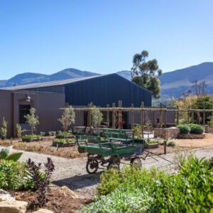 A garden with a green cart in front of a building at Rivergate Guest Farm in Stanford