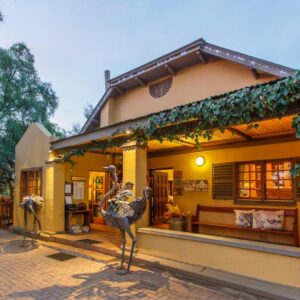 A house with two statues in front of it at Riverside Guest Lodge in Oudtshoorn