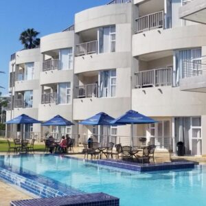 A hotel with a swimming pool in front of a building at Riviera Hotel Hartenbos in Mossel Bay
