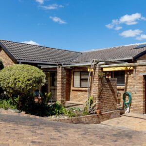 The brick cottage with a brown door and driveway at Rosemary's Cottage in Hermanus