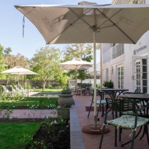 A patio with tables and chairs and umbrellas at Rozenburg Guest House in Stellenbosch