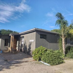 A house with a palm tree in front of it at Rusthof Accommodation in Gansbaai