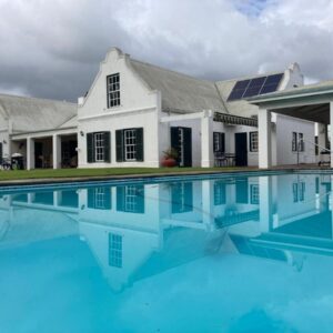 A large white house with a swimming pool in front of it at Sanddrif Stellenbosch Guest Farm in Stellenbosch