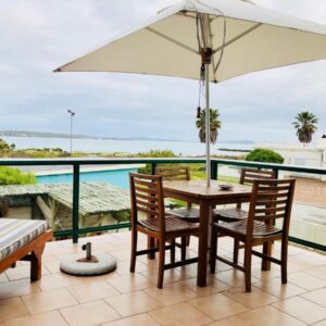 A patio with a table and chairs and an umbrella at Sandra's Guest House in Langebaan